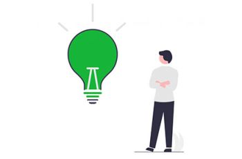 Man standing next to a large green lightbulb